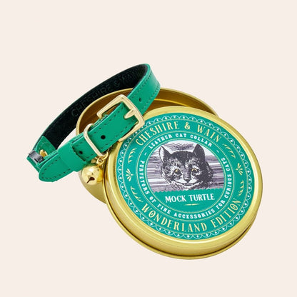 A bright green cat collar with brass hardware, displayed on a round golden tin that has a illustration of a cat's face in the center, presented in a special edition Mock Turtle gift tin.